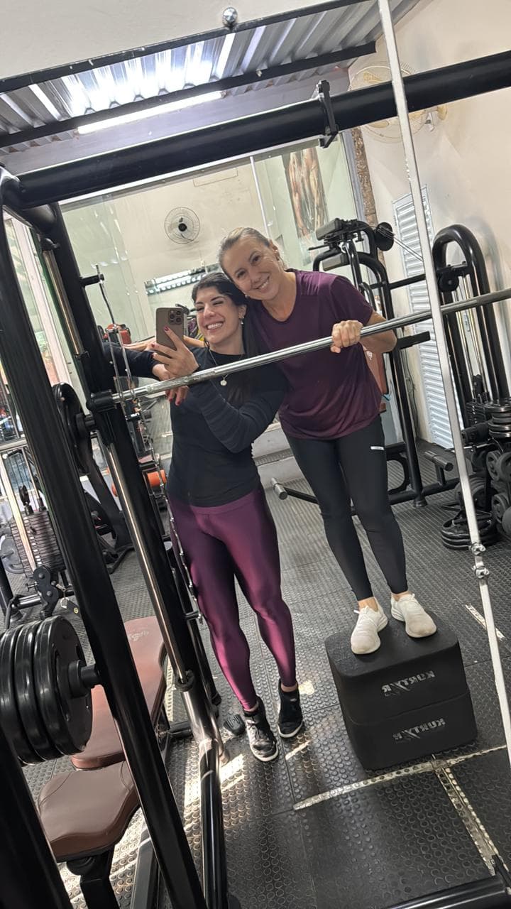 Bárbara Zalla e uma aluna sorrindo na estação de agachamento